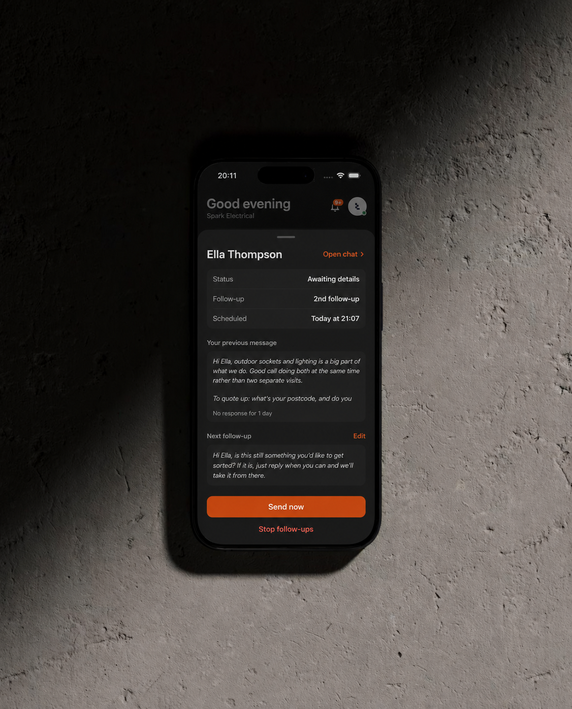 Tragent scheduling a customer follow-up on a phone against a concrete wall
